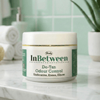 Herby InBetween De-Tan cream jar displayed in a clean bathroom setting with soft green tiles and minimal decor.